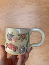 Load image into Gallery viewer, Hand holding a decorative lock with cartoon designs on a wooden surface
