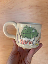 Load image into Gallery viewer, Hand holding a mug with a cartoon character and text on a wooden surface

