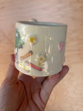 Load image into Gallery viewer, Hand holding a ceramic mug with illustrations on a wooden surface
