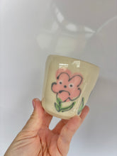 Load image into Gallery viewer, Ceramic cup with a pink flower design held by a hand against a white background
