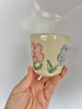 Load image into Gallery viewer, Hand holding a small ceramic cup with floral designs on a white background
